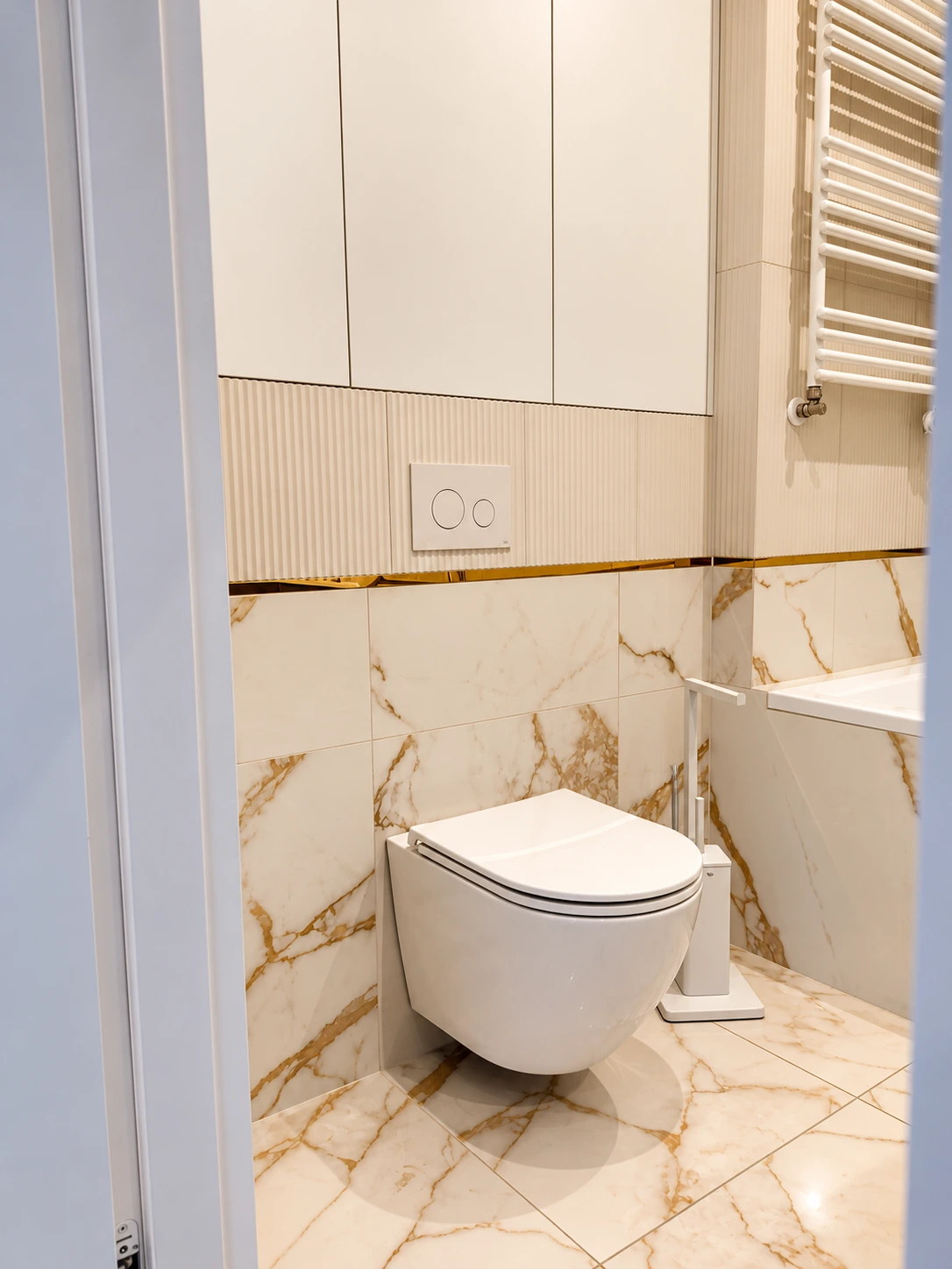 Strefa WC z marmurową okładziną, złotym detalem i zabudową